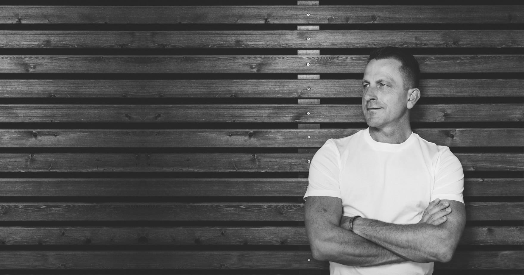 Ralf W. Müller vor einer dunklen Holzwand, der Blick ruhig zur Seite