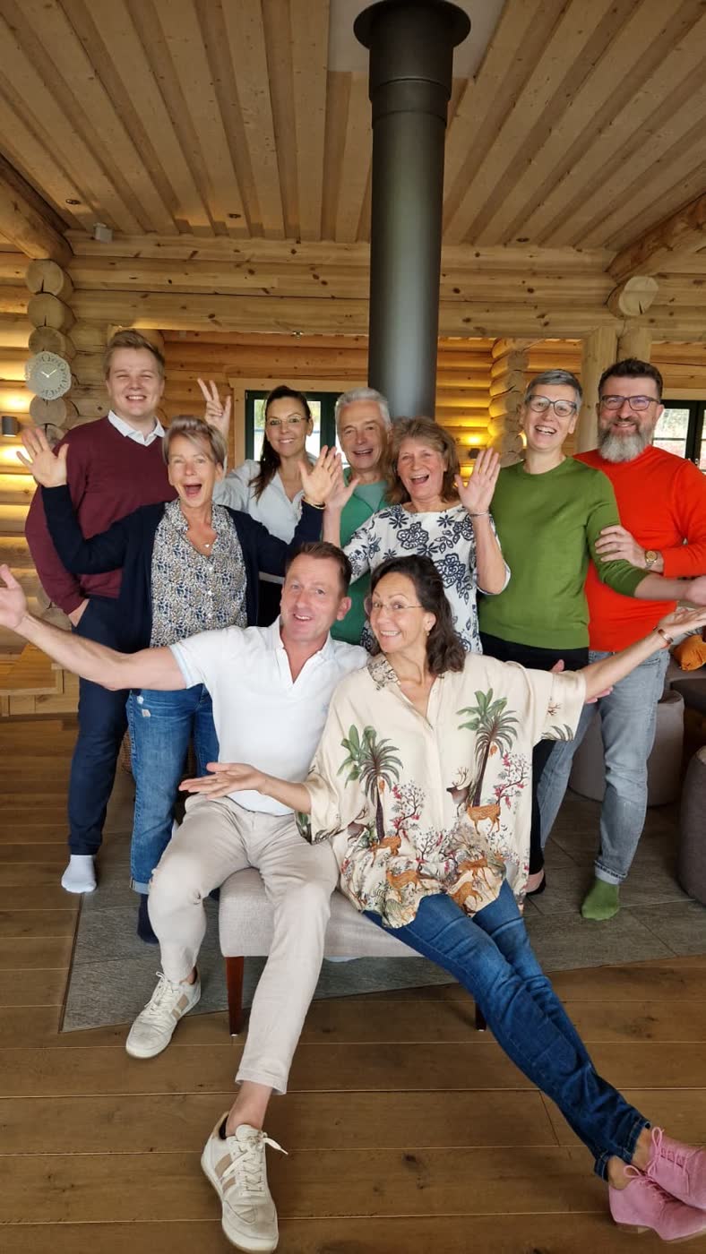 Fröhliche Seminargruppe mit Ralf in einer Holzhütte