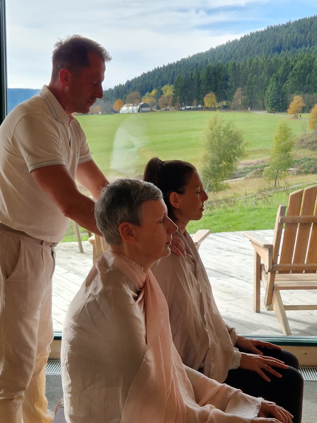 Ralf arbeitet mit einer Teilnehmerin auf einer Terrasse mit Bergblick